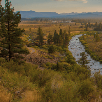 Looking down at the Legacy Trail with a foot bridge over the Truckee River and mountains behind it. 