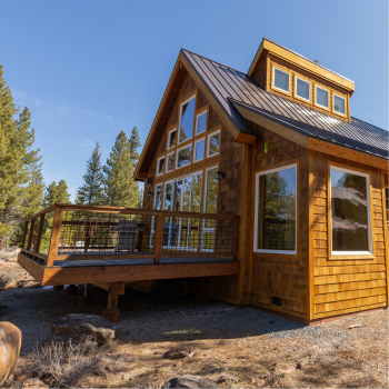 A wooden house with a deck on a sunny day with blue skies. 