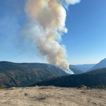 A large cloud of smoke coming from a mountain side. 