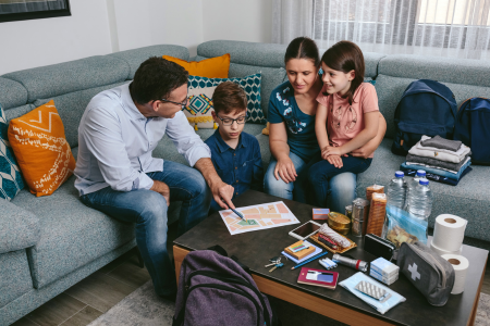 Mother, father and two kids sitting in livingroom looking at their emergency plan. 