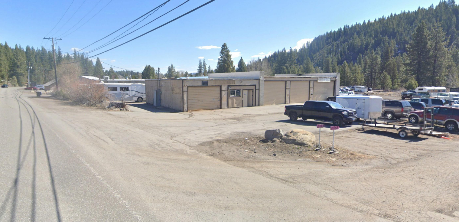 Rendering of West River Street- road with powerlines, parking lot and square sheds, 